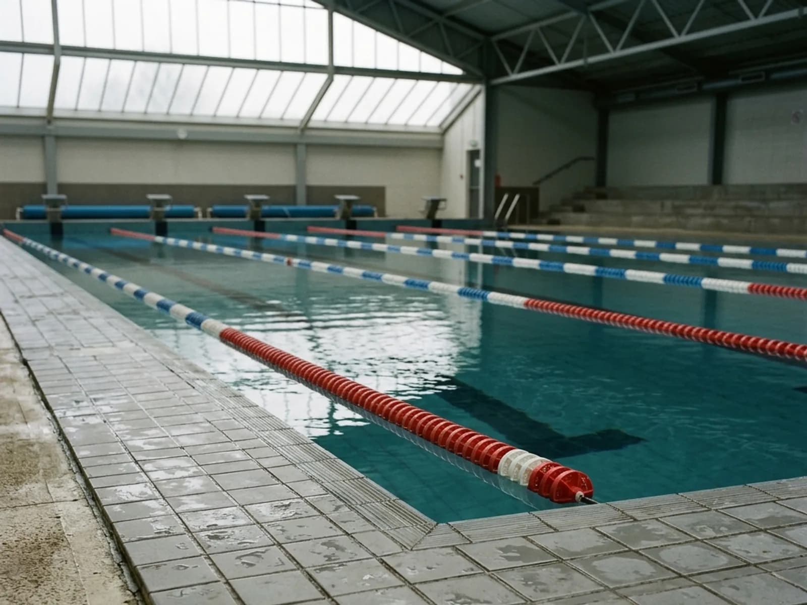 A close view of the edge of a swimming pool with calm water under overcast light.